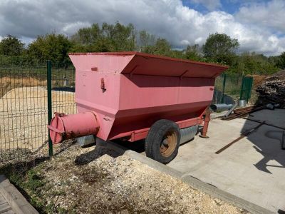 un camion-benne rose garé devant un terrain clôturé