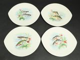 four plates with fish painted on them sitting on a table