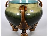 un vase vert et marron posé sur un socle