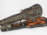 un vieil étui à violon contenant un violon, posé sur une surface blanche