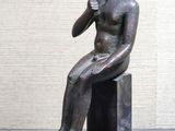 statue d'un garçon assis sur un bloc, la main posée sur le menton