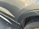 un chat assis sur le côté d'une voiture garée