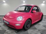 une Coccinelle VW rose garée dans une salle blanche au sol à carreaux