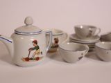 a white tea pot with blue trim and a tea cup and saucer with a picture of a boy on it