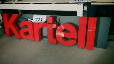 une grande enseigne rouge sur laquelle est inscrit « Kartell »