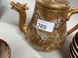 a gold teapot sitting on a table next to a stack of plates