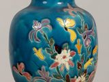 a blue vase with flowers on it sitting on a table