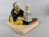une figurine représentant un homme et une femme assis sur un banc