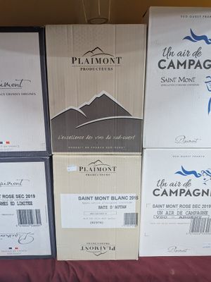 Plusieurs cartons de vin sont empilés sur une table dans une pièce.