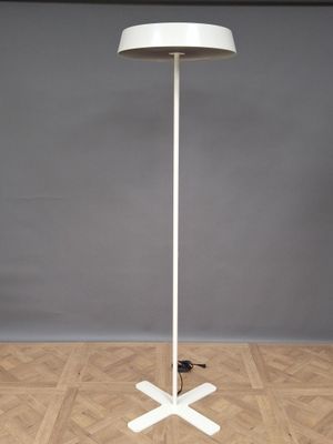 Lampadaire en métal laqué blanc sur piètement cruciforme.