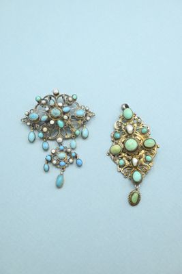 two antique brooches with turquoise and white stones on them