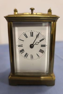 une petite horloge en or avec des chiffres romains