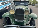 an old green car parked in front of a building