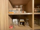 a wooden shelf filled with wine glasses and other items