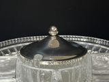 a glass plate with a silver lid on a black background