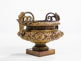a gold vase that is sitting on a wooden stand