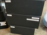 three black boxes are stacked on top of each other on the floor