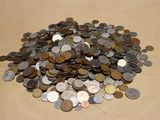 a pile of coins sitting on a table next to a cell phone