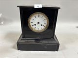 une petite horloge noire avec un cadran blanc posée sur une table