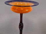 a small glass bowl on a stand on a gray surface