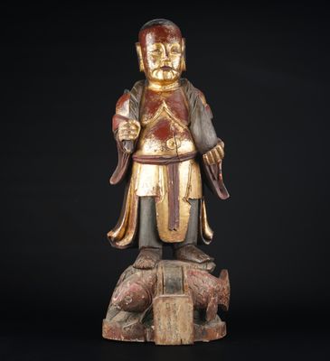 une statue en bois représentant un homme tenant une épée et debout sur un rocher