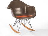 a rocking chair with a brown seat and orange cushion