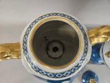 a blue and white vase with a gold decoration on it