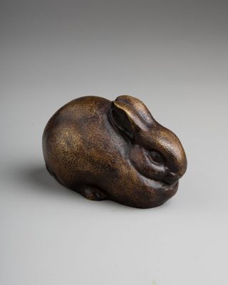 an image of a bronze sculpture of a rabbit on a white surface