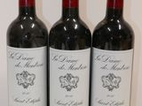 three bottles of red wine are lined up on a white surface