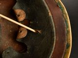 a wooden stick sticking out of a bowl with paint on it