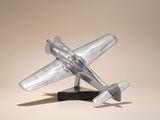une maquette d'avion en argent posée sur un socle noir