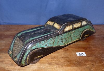une vieille petite voiture jouet verte et noire posée sur une table en bois