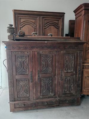 une grande armoire en bois ornée de sculptures sur le dessus