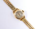 une image d'une montre-bracelet en or sur une surface blanche