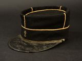 an old black hat with a gold band on a black background