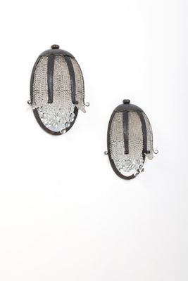 une paire de boucles d'oreilles noires et argentées sur fond blanc