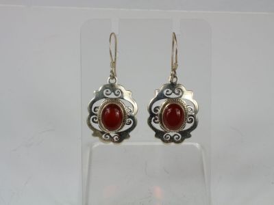 a pair of silver and red stone earrings on a clear surface