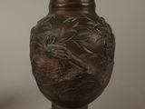 a bronze vase with a bird on it sitting on a table