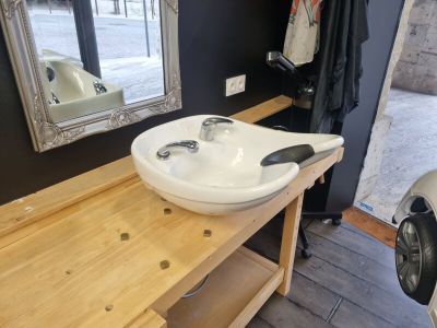 un lavabo blanc posé sur un plan de travail en bois, à côté d'un miroir