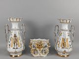 trois vases blancs ornés de motifs dorés, disposés les uns à côté des autres