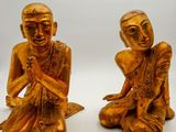 pair of golden buddha figurines sitting on a white surface