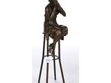 une statue en bronze représentant une femme assise sur un tabouret