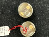 two silver coins with a price tag on them sitting on a table