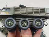 a person holding a toy army vehicle in their hand