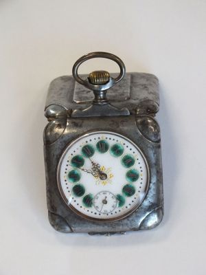 une petite horloge en argent avec un cadran vert, posée sur une table