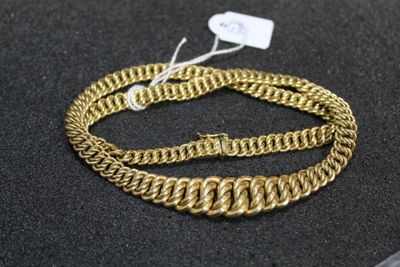 a close up of a gold chain bracelet on a black surface