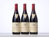 three bottles of red wine are lined up on a table
