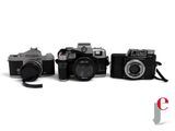 three cameras sitting next to each other on a white surface