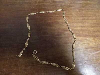 une chaîne en or à laquelle est accrochée une bague, posée sur une table