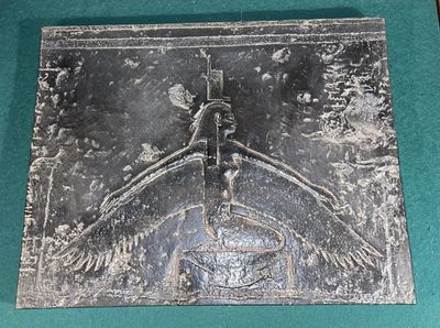a metal plaque with a bird on it on a green surface